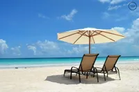 Two beach chairs and an umbrella on a beach.