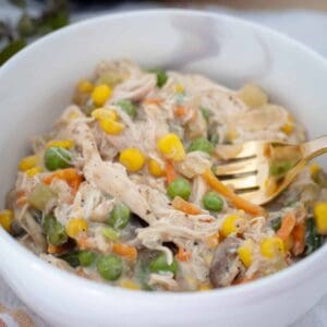 Creamy chicken and vegetable soup in white bowl.